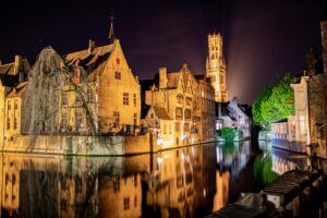 Captivating night scene of Bruges with historic buildings and canal reflections under starlit sky.